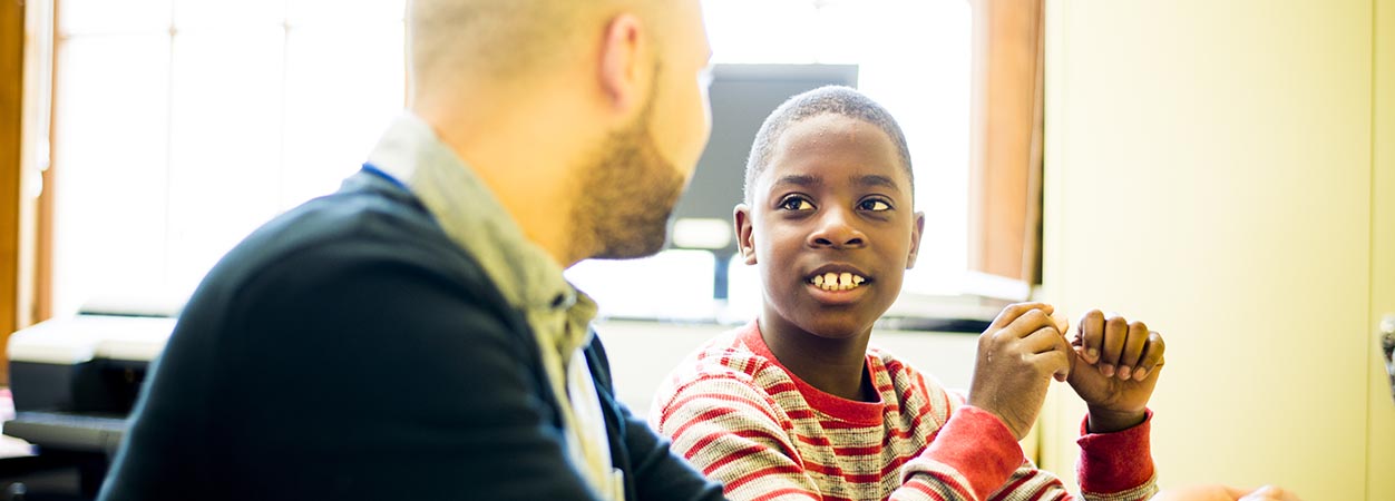 A student smiles at his counselor in the classroom.