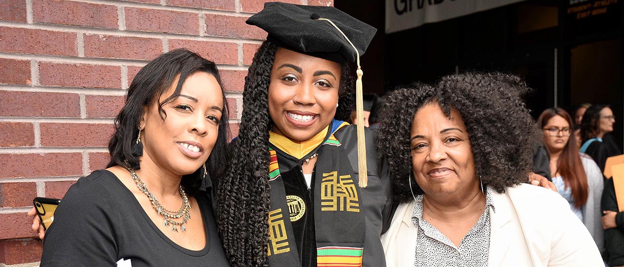A School of Education graduate with two family members at commencement.