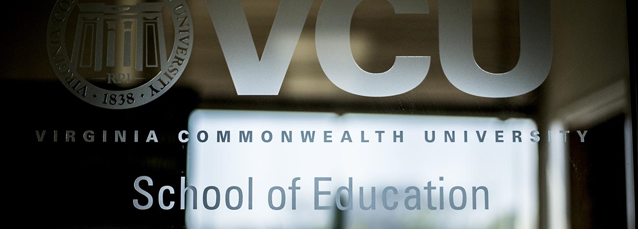 A glass door in OliverHall, with the words Virginia Commonwealth University School of Education visible. The VCU is partially visible at the top.