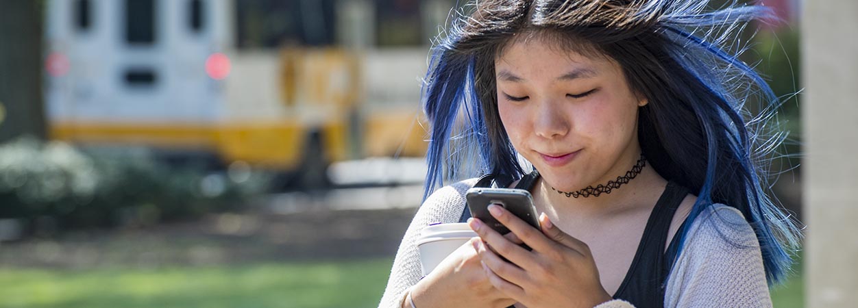 An international student checks messages on her smartphone.