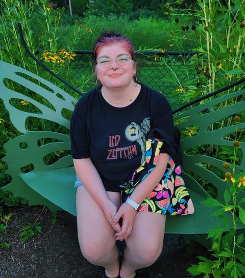 Alie Linens, VCU SOE sophomore, sits outdoors on a butterfly bench.