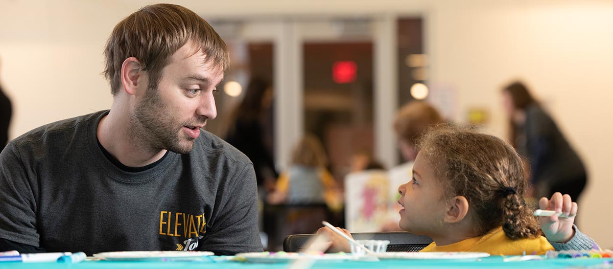 Jason Sandahl, an M.T. student in early and elementary education, helps one of the children from the Child Development Center with an activity.