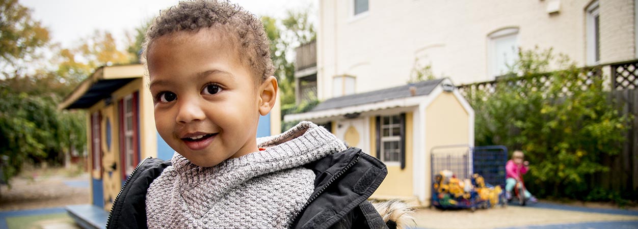 A child smiles in the outdoor play area of the VCU Child Development Center.