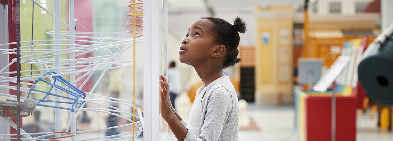A K-12 student looks up at a STEM display.