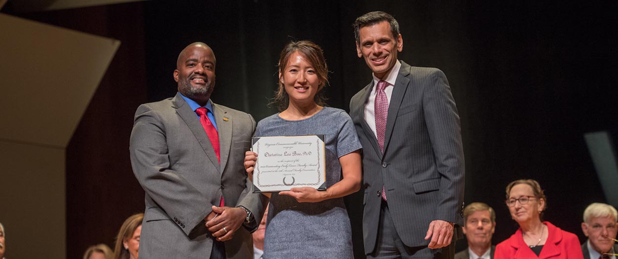 Christine Lee Bae, Ph.D., receives the Outstanding Early Career Faculty Award from VCU President Michael Rao, Ph.D., and Andrew P. Daire, Ph.D., dean of the School of Education. (Photo by Tom Kojcsich, University Relations)