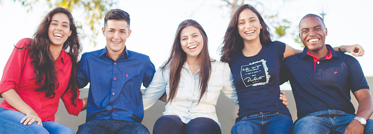 A group of five students sit next to each other, smiling. (Photo courtesy Naassom Azevedo /Unsplash)