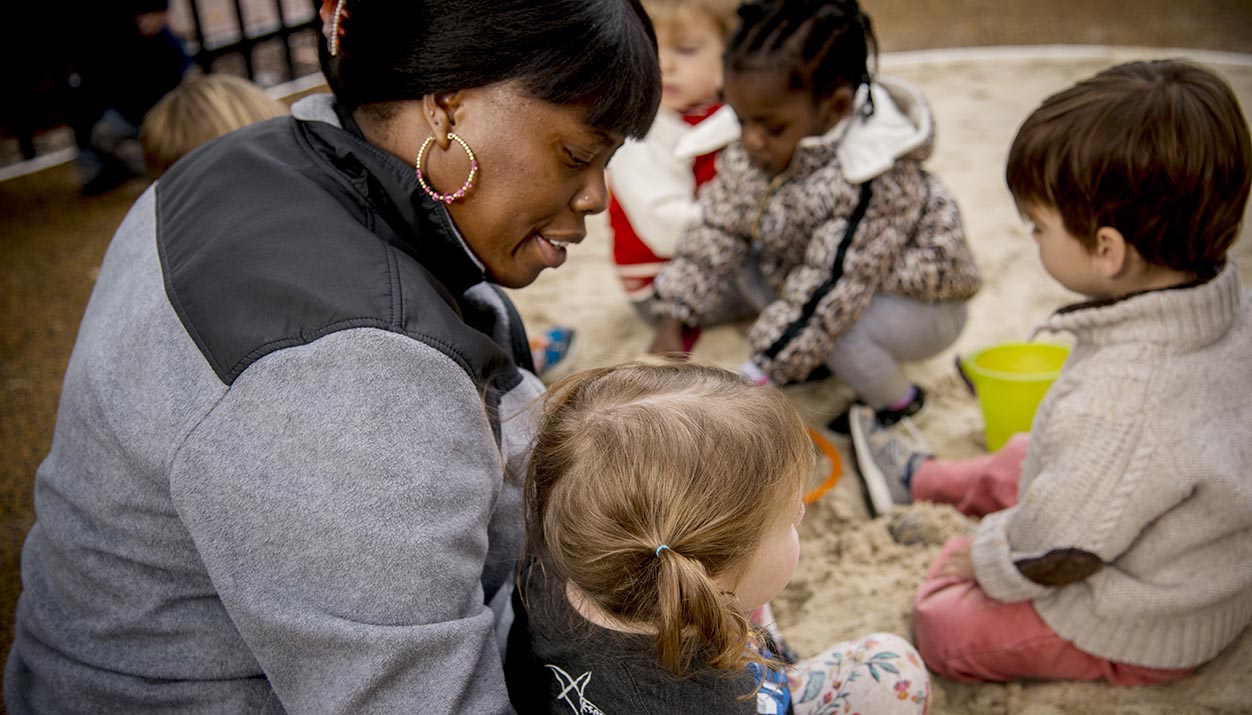 In a photo taken before the COVID-19 pandemic, Nakita Battle, an assistant teacher at the VCU Child Development Center, takes care of children in the center's outdoor play area.